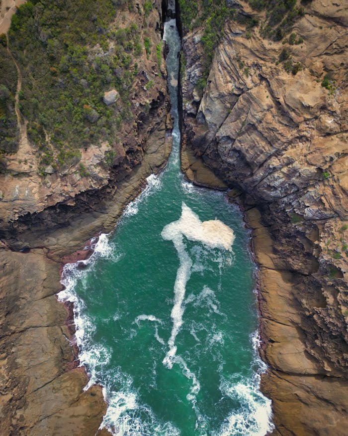Aerial view of turquoise waters cutting through rocky cliffs at Newcastle, Australia.